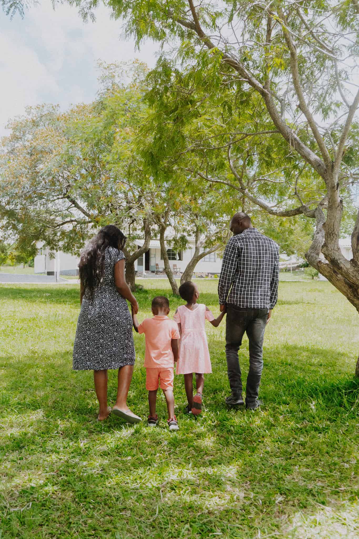 Family of four walking away from the camera in green grass